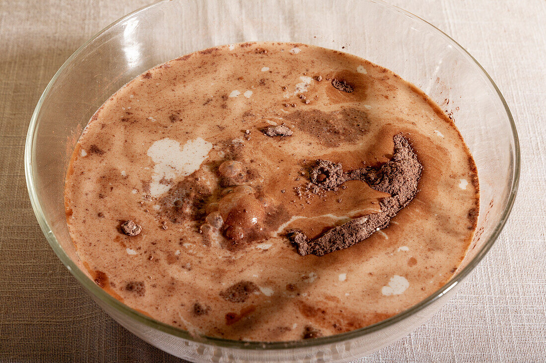 High angle Closeup of a glass bowl filled with milk and powdered chocolate placed on table