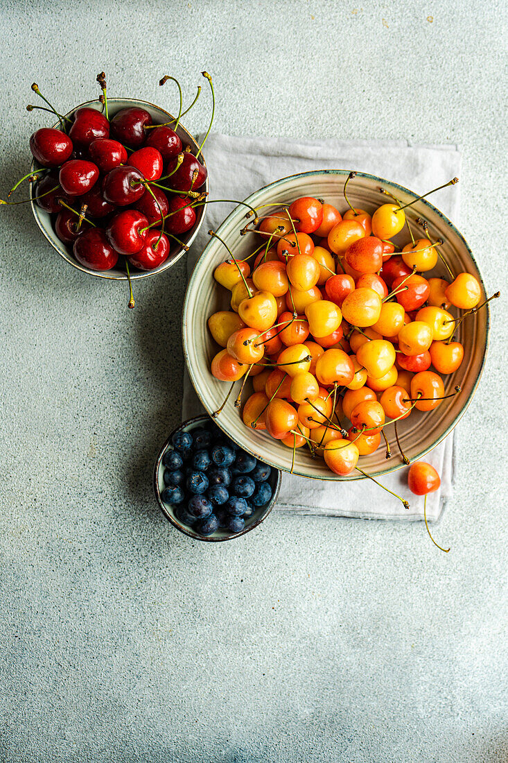 Bowl with organic ripe red and white sweet cherries and bowl with blueberry on the kitchen table