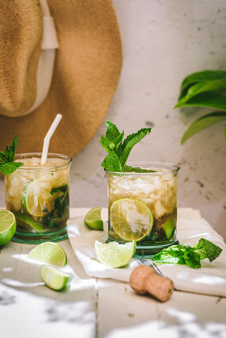 Gläser mit kaltem Alkohol Mojito-Cocktail mit Cava und frischen Limetten, serviert mit Eis und Minzblättern auf einem Tisch