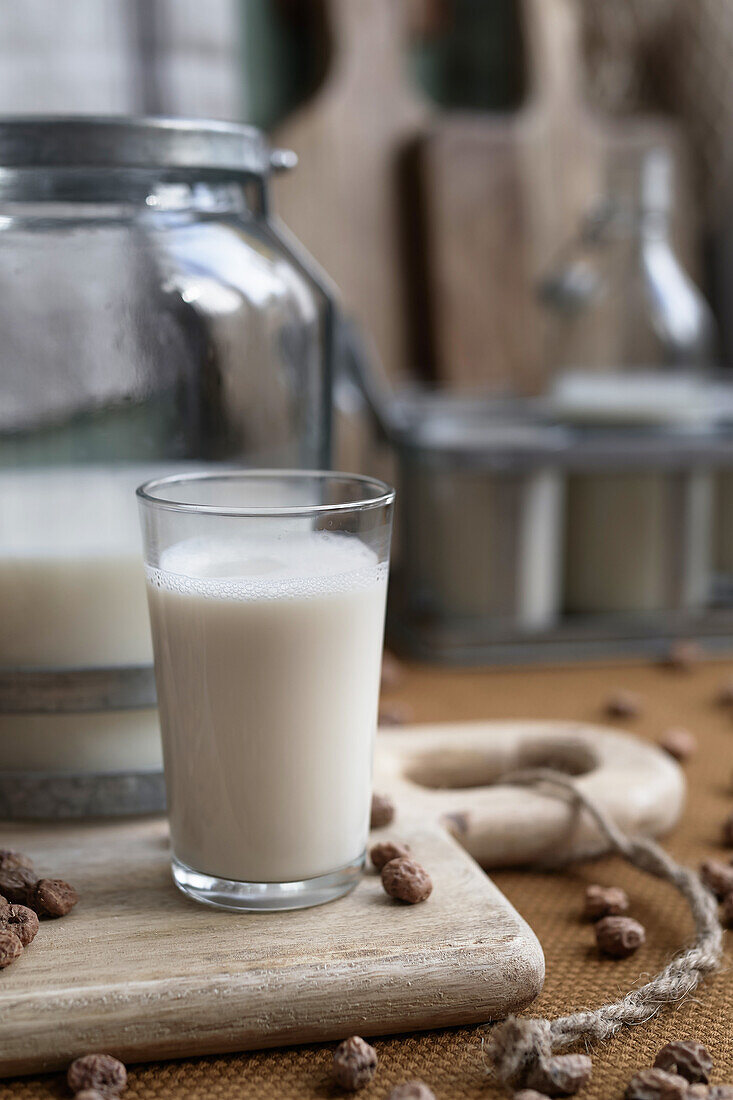 Hausgemachtes Bio-Horchata-Getränk, serviert in einem modernen transparenten Glas in der Nähe der Flasche auf einem Holztisch in einer rustikalen Küche