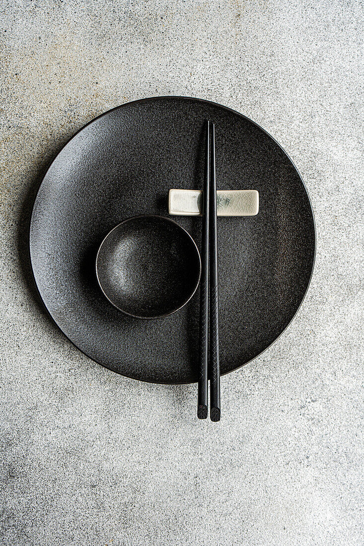 Minimalistischer gedeckter Tisch mit Geschirr und Besteck auf Betonhintergrund