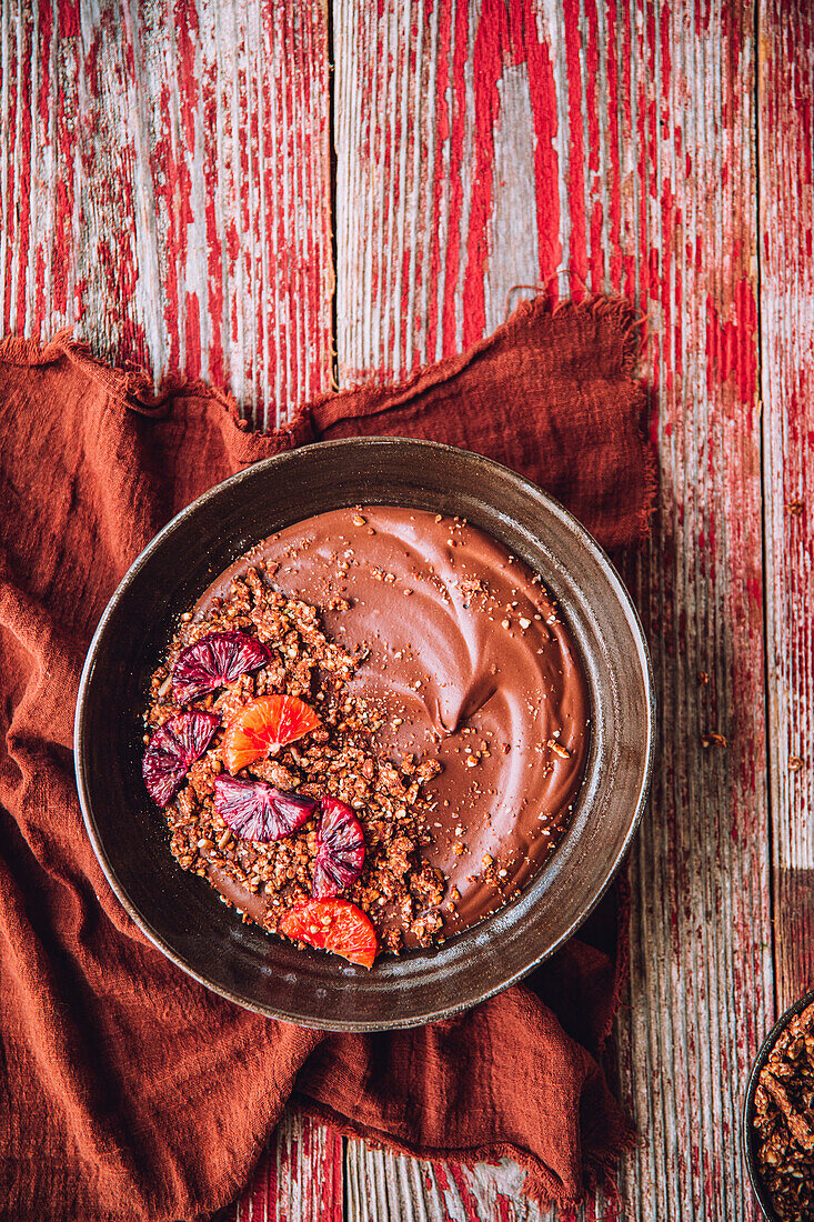 Top view of bowl filled with chocolate smoothie placed near red fabric on wooden table