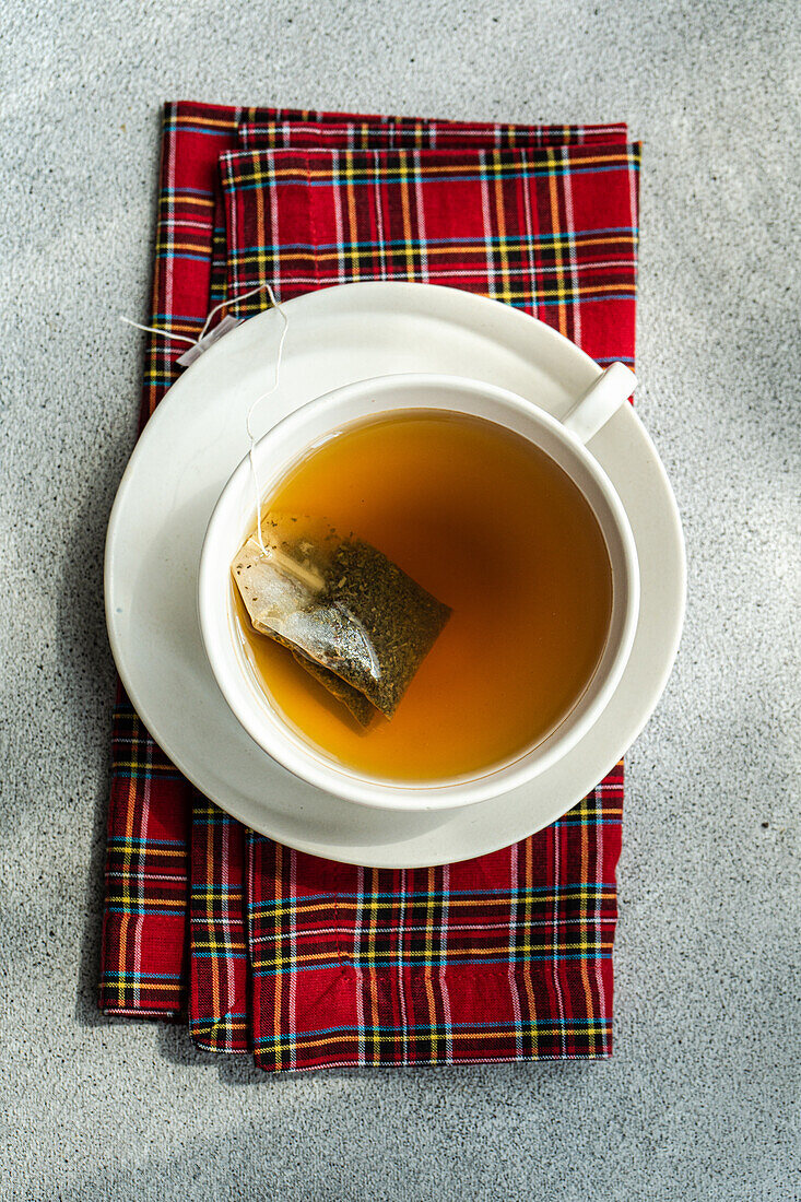 Draufsicht auf eine weihnachtliche Tasse Tee auf einer roten Serviette auf einem grauen Tisch
