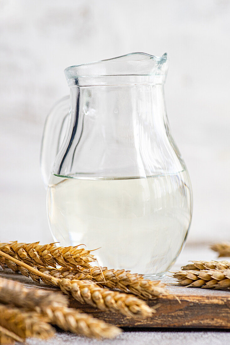 Traditional Ukrainian alcoholic drink made from wheat and known as Gorilka served in transparent jar placed on cutting board against blurred background