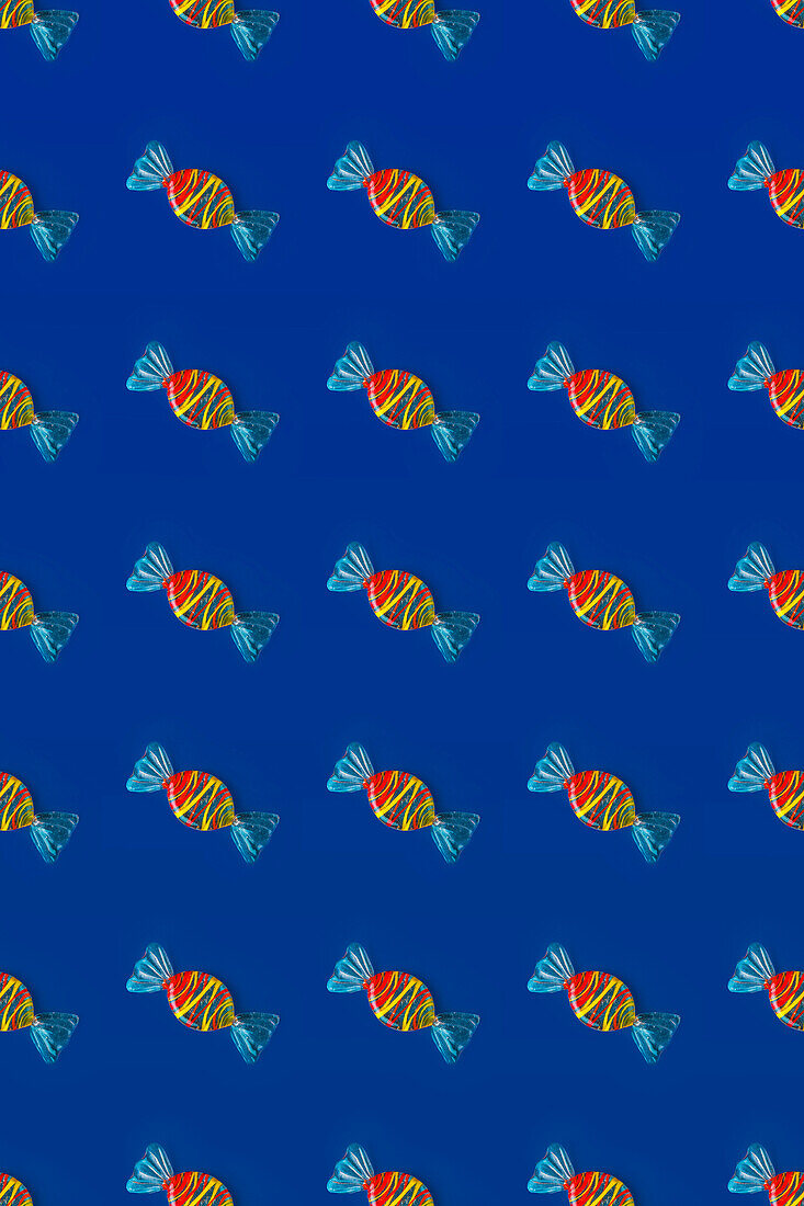 Top view of pattern of whole sweet crystal candies arranged on blue background