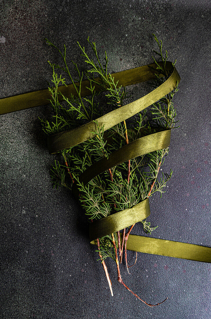 Draufsicht auf grüne Tannenzweige, die mit einer Schleife als Symbol für das Weihnachtsfest geschmückt sind