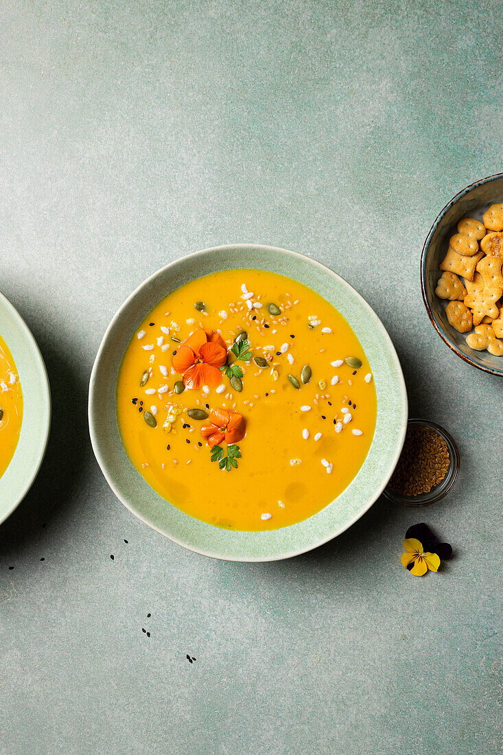 Top view of appetizing vegetarian pumpkin cream soup with herbs and sesame seeds served in bowls on table