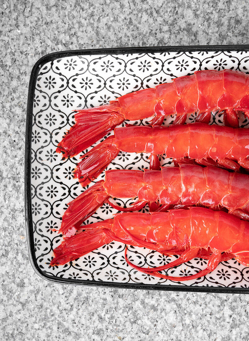 Nahaufnahme von oben von frischen rohen Shrimps auf einem Tablett über einem grauen Marmortisch