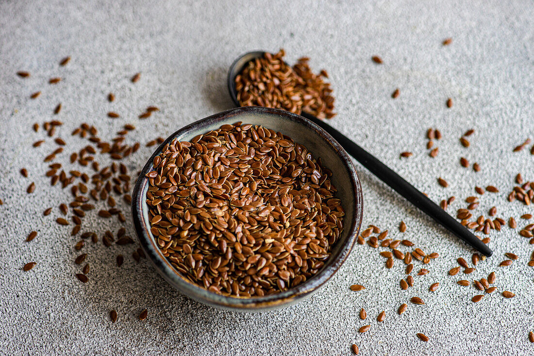 Bowl with raw oragnic flax seeds on concrete table