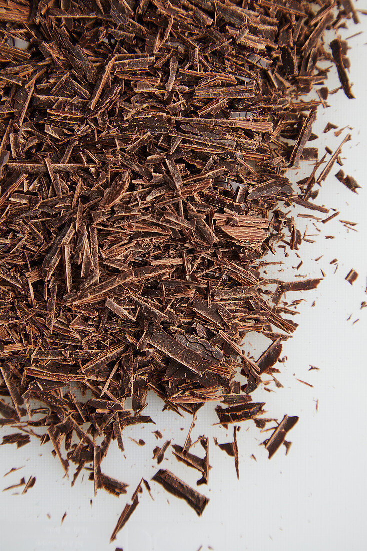 High angle of many chocolate shavings placed on white table for sprinkling dessert