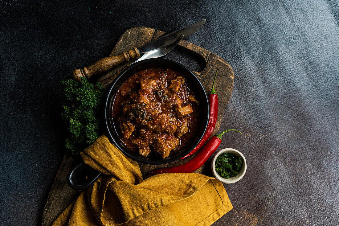 Traditional Georgian dish Ostri served in the bowl on wooden cutting board