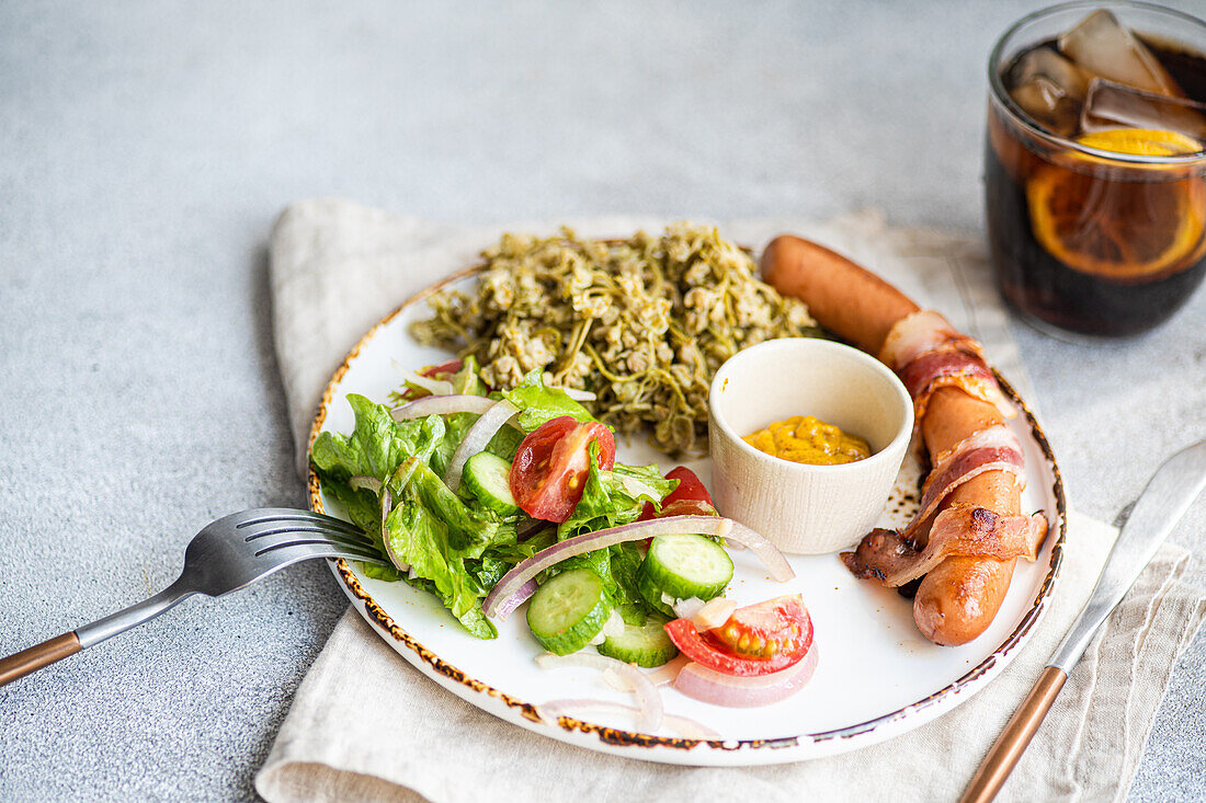 Vegetables and sausages on plate served with glass of cola drink