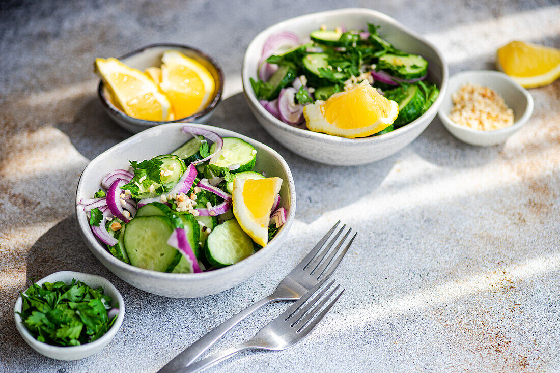 From above of healthy vegetables salads with organic cucumber, red onion, coriander and chopped nuts placed in a concrete table