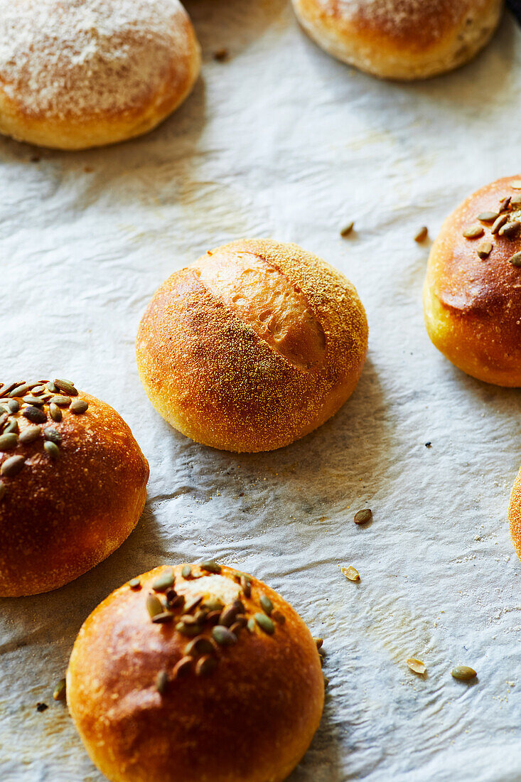 Appetizing homemade baked buns with crispy crust and seems on table in bakery