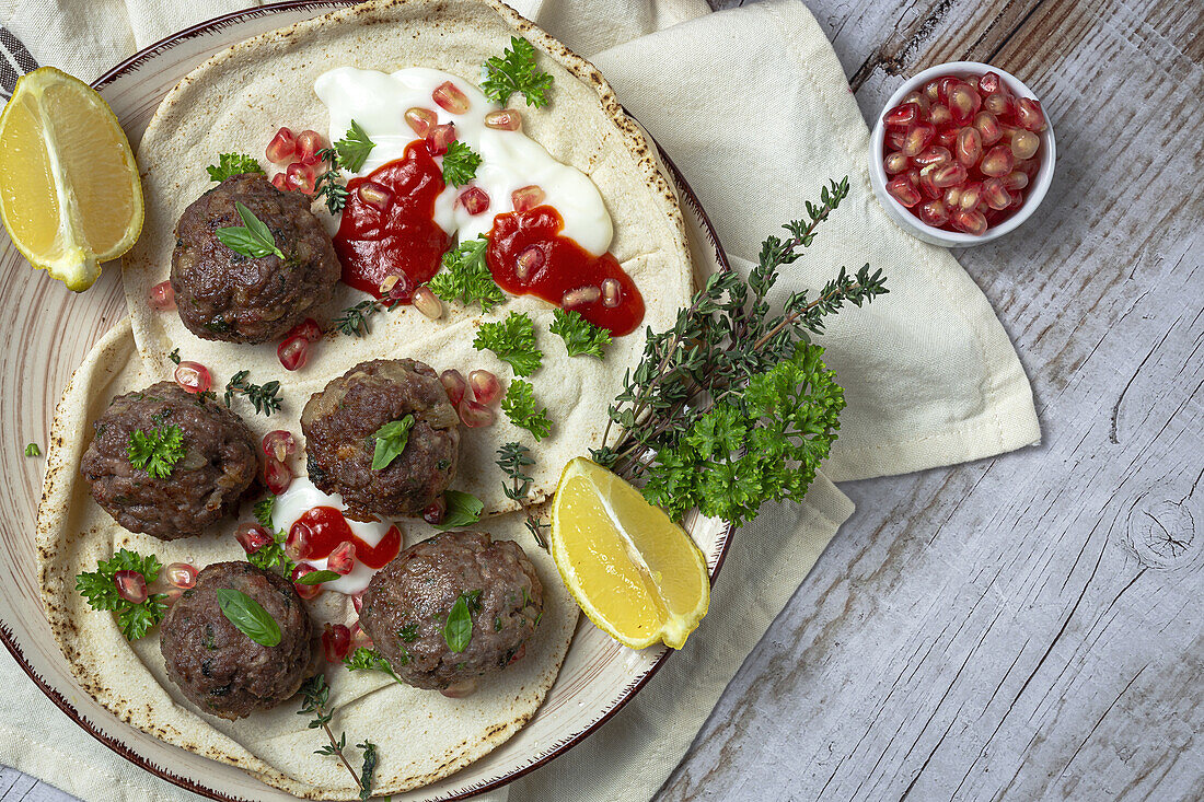 Traditionelle hausgemachte Rind- und Lammfleischbällchen mit arabischem Brot, Tomatensauce, Granatapfel und Kräutern. Halal-Essen