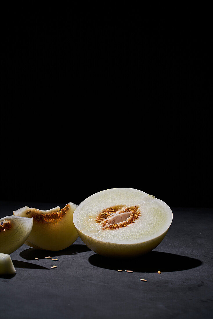 Side view of a fresh melon cut in half on black background