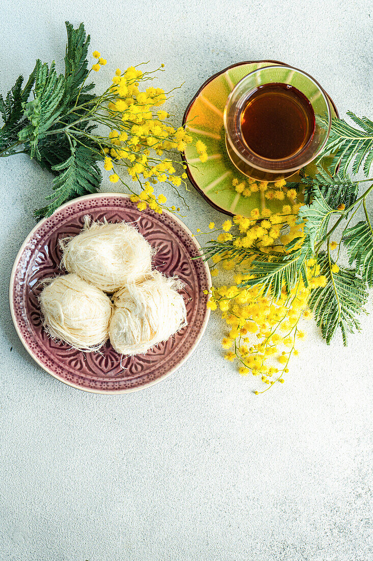 Türkischer Genuss und Tee auf dem Tisch mit gelben Mimosenblüten