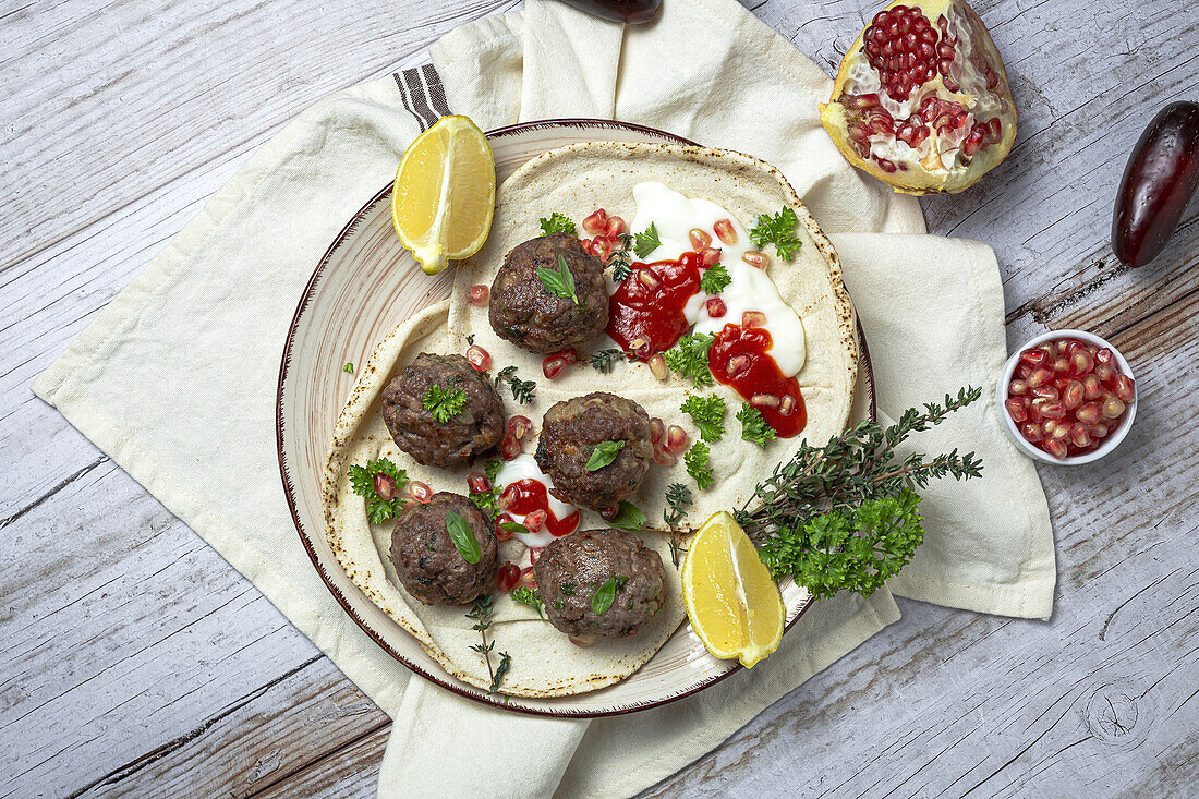 Traditionelle hausgemachte Rind- und Lammfleischbällchen mit arabischem Brot, Tomatensauce, Granatapfel und Kräutern. Halal-Essen