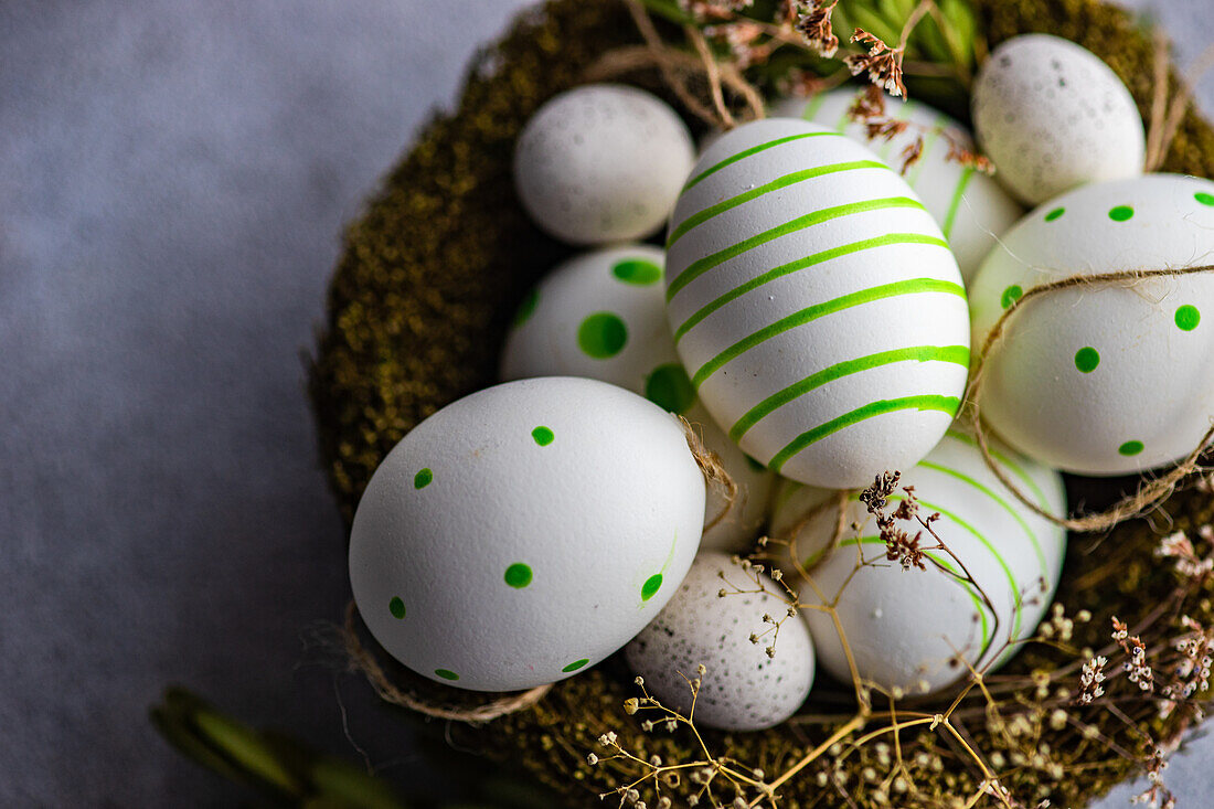 Von oben Nest voll von farbigen Eiern als Osterferien Konzept auf konkreten Hintergrund