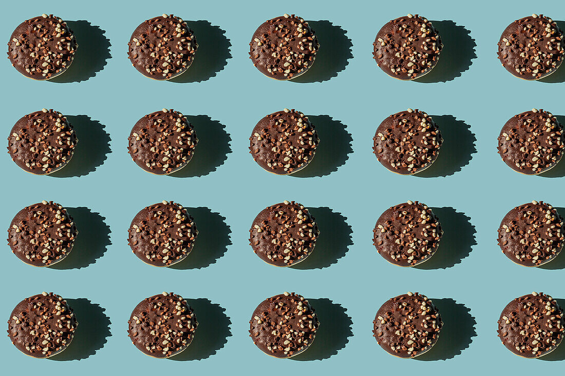 Top view of many donuts without hole covered with chocolate and nuts on blue background