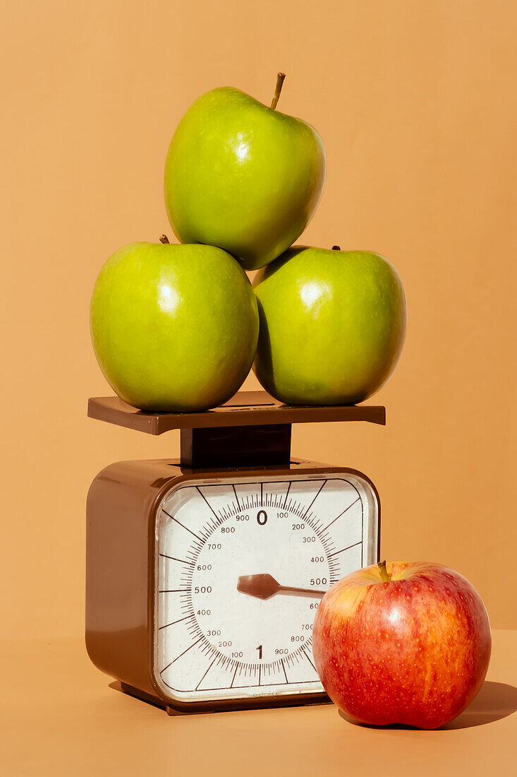 Fresh and juicy red and green apples on weighing scale as part of healthy calorie controlled diet on colored background