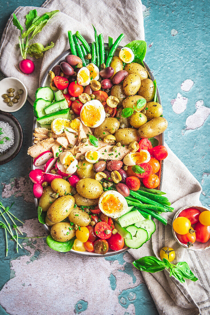 Draufsicht auf einen köstlichen Nicoise-Salat mit frischem Gemüse in einem Tablett auf dem Tisch