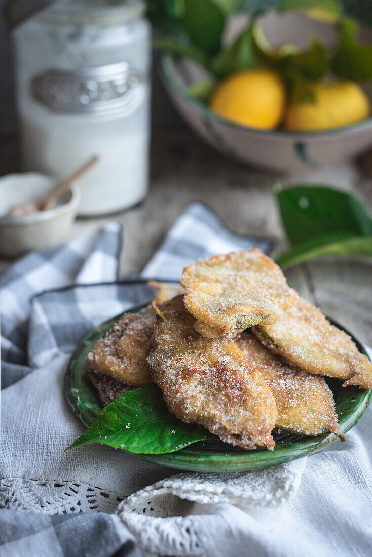 Von oben Teller mit Paparajotes, einem typischen Dessert aus Murcia in Spanien, hergestellt aus Zitronenblättern und bestreut mit Zucker auf einem rustikalen Holztisch