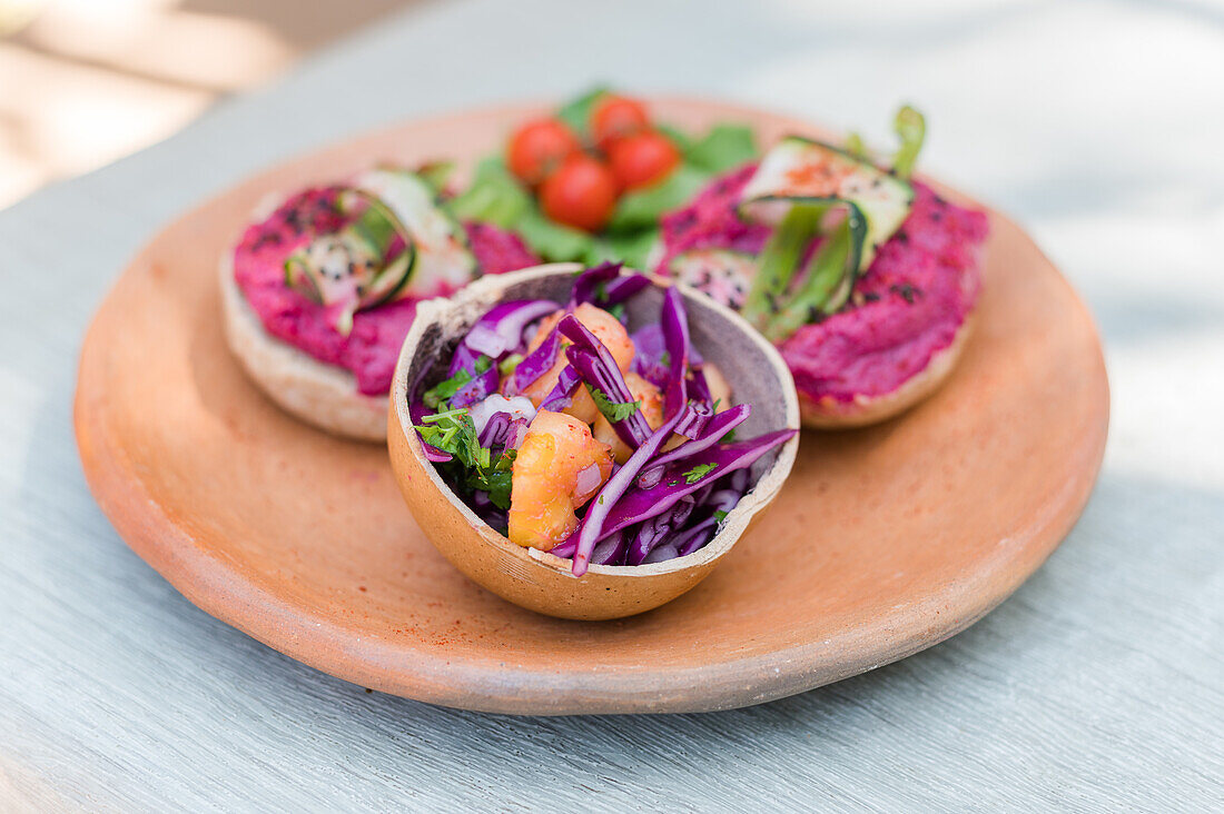 Frischer Gemüsesalat aus lila Kohl, Karotten und Kräutern, serviert in einer Schüssel auf einem Teller mit vegetarischen Sandwiches zum Mittagessen
