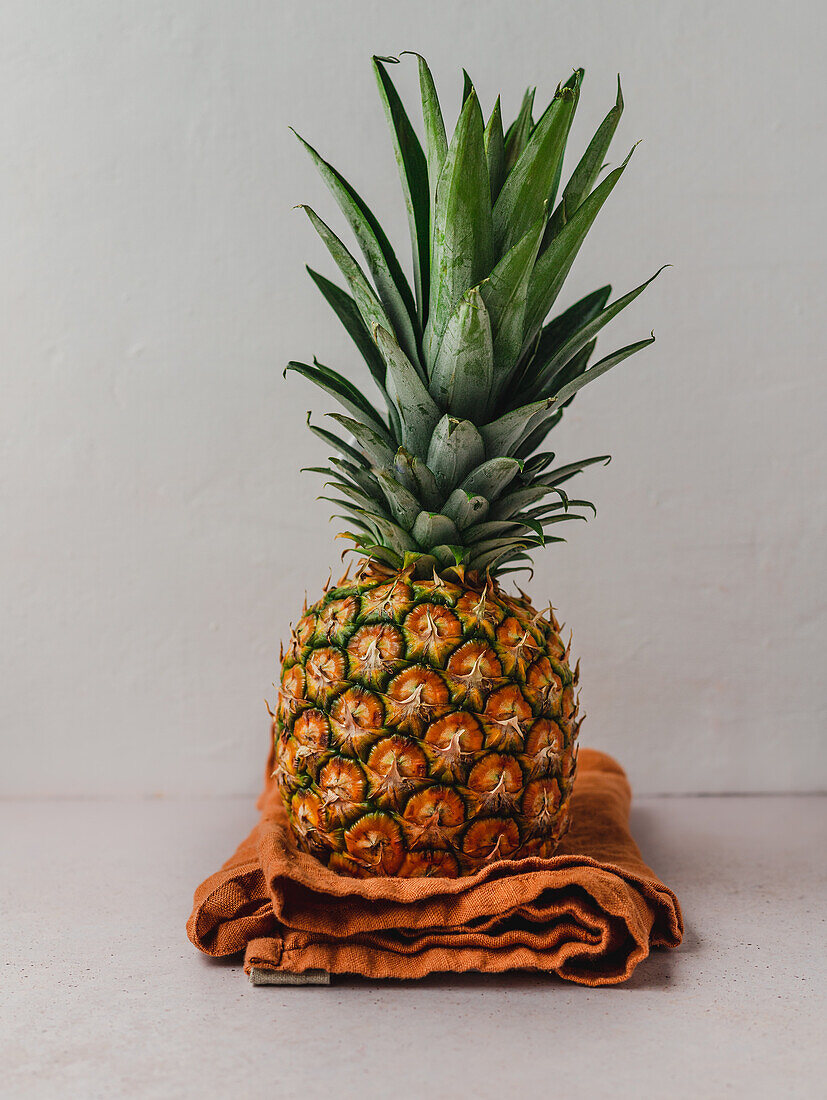 Ripe whole sweet pineapple placed on napkin on table in kitchen