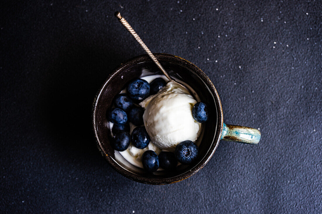 Von oben Schüssel voll mit köstlichen reifen Blaubeeren auf schwarzem Hintergrund platziert