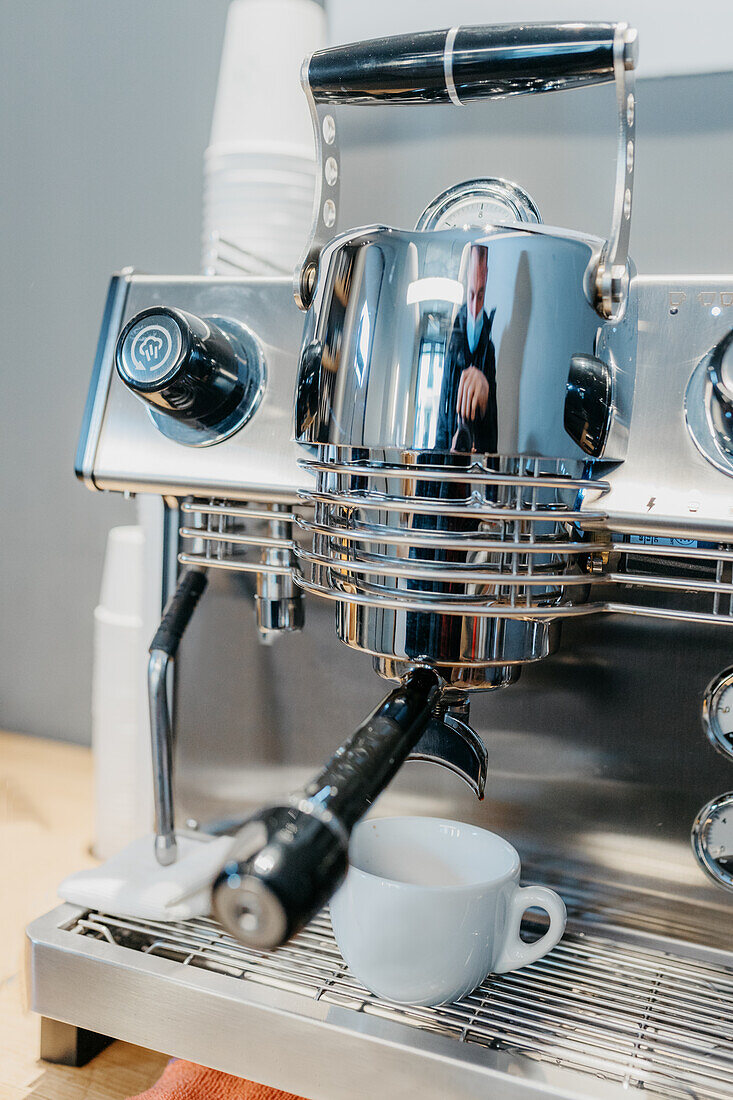 Moderne professionelle Kaffeemaschine gießt frischen heißen Kaffee in eine weiße Tasse in einem Café bei Tag
