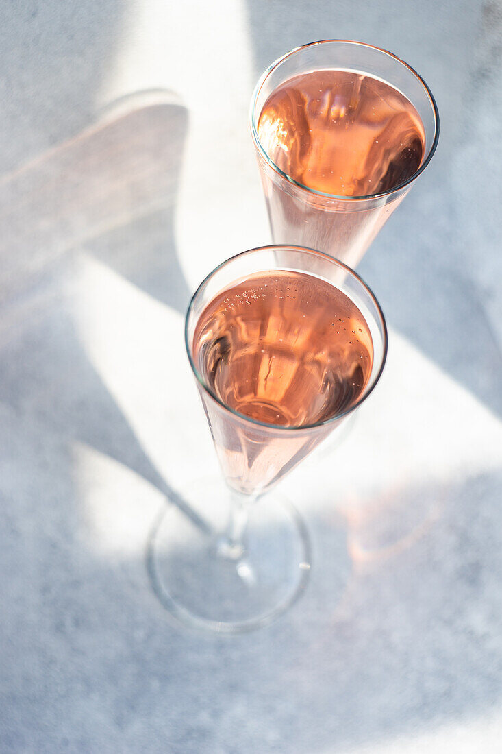 Rosensekt oder Champagner in Kristallgläsern auf hellem Hintergrund an einem sonnigen Tag