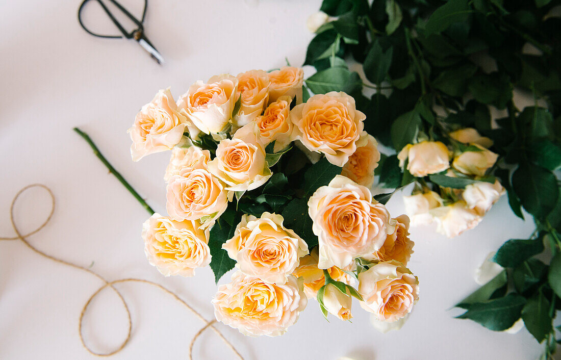 Draufsicht auf blühende, duftende gelbe Rosen in einer Vase auf einem weißen Tisch in einer Blumenwerkstatt