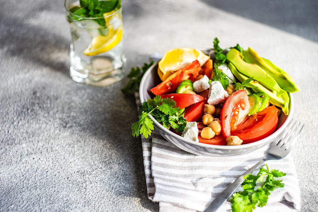 From above healthy salad with organic seasonal vegetables and avocado served on concrete table