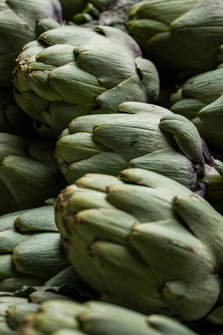 Full frame of bunch of fresh green artichokes placed on stall in local market