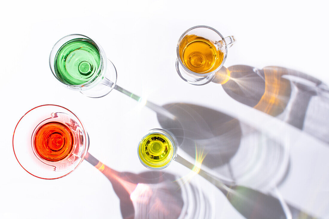 Top view of different types of glasses with colorful liquid inside on white background