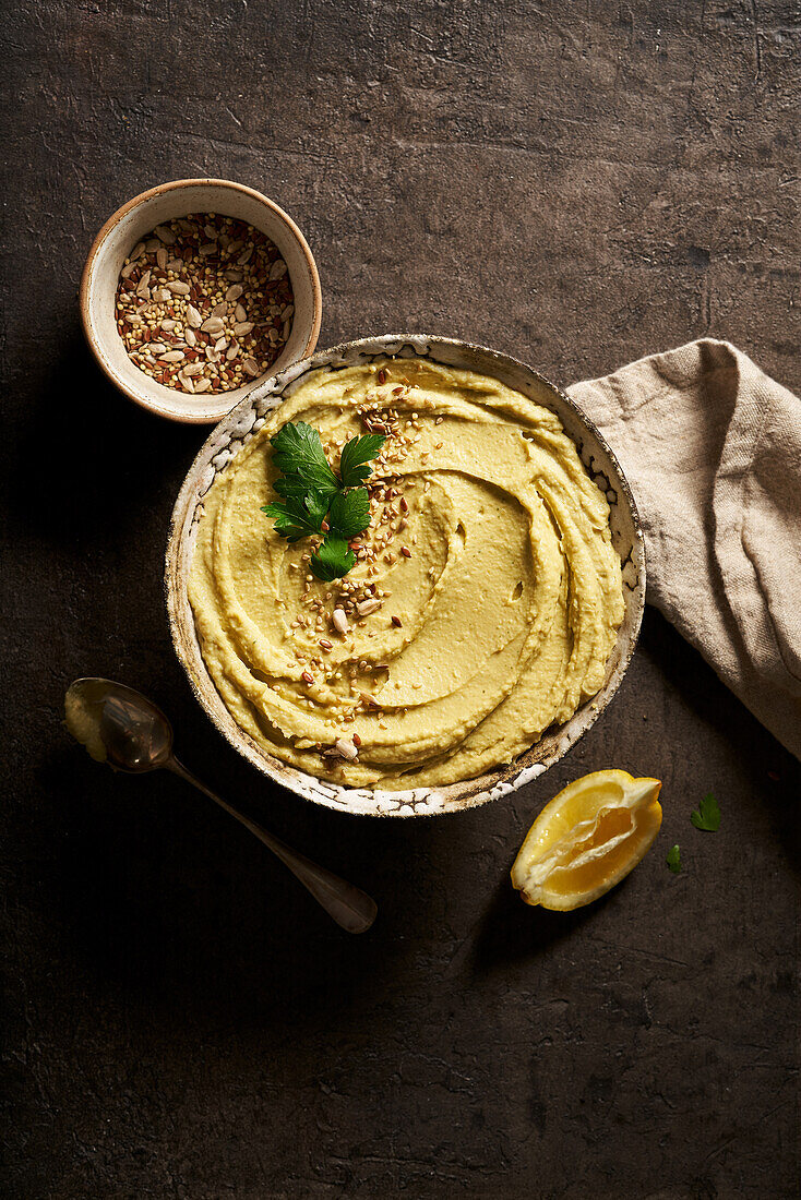 Top view bowl of delicious homemade hummus served on table with slice of lemon and chopped nuts