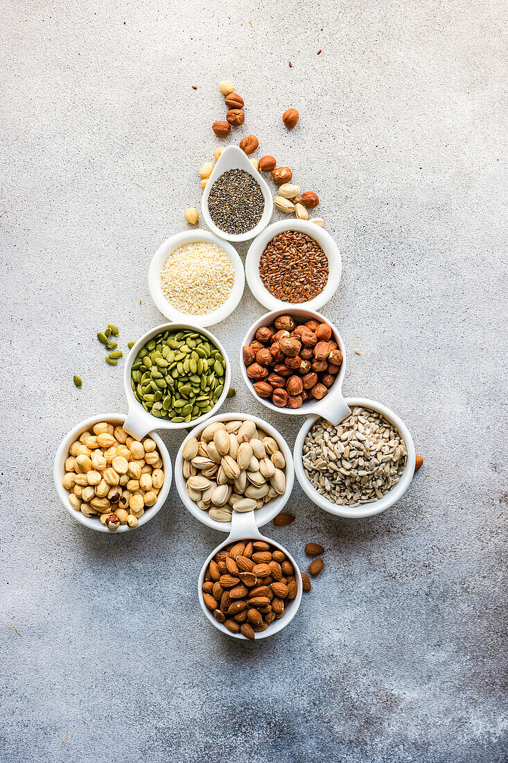 Top view of bowls full of nuts and seeds on concrete background