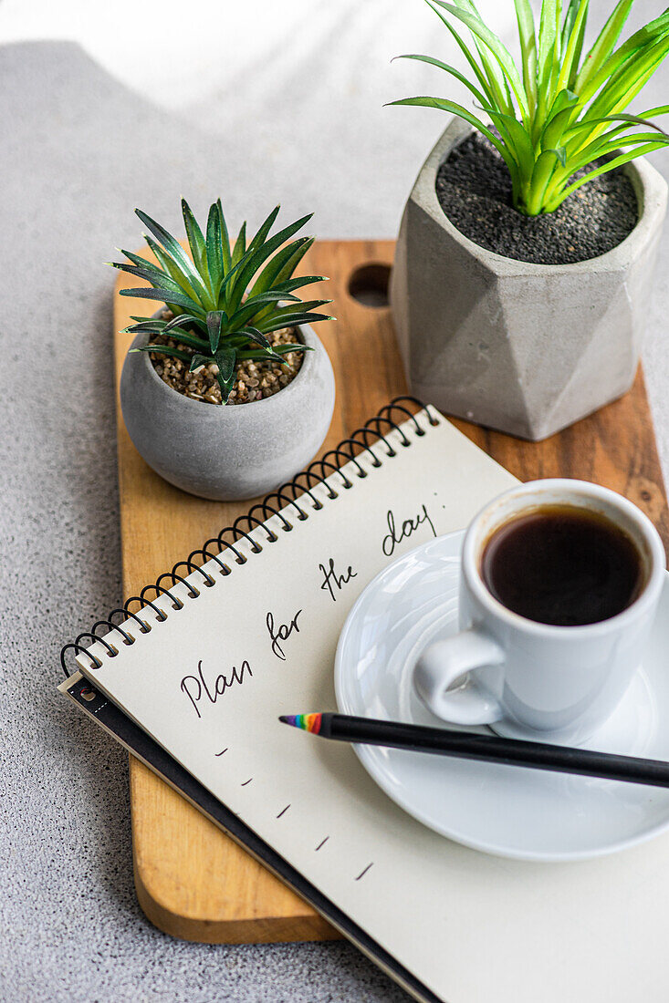 Plans for the day and morning cup of coffee on the table with green plants in the pot