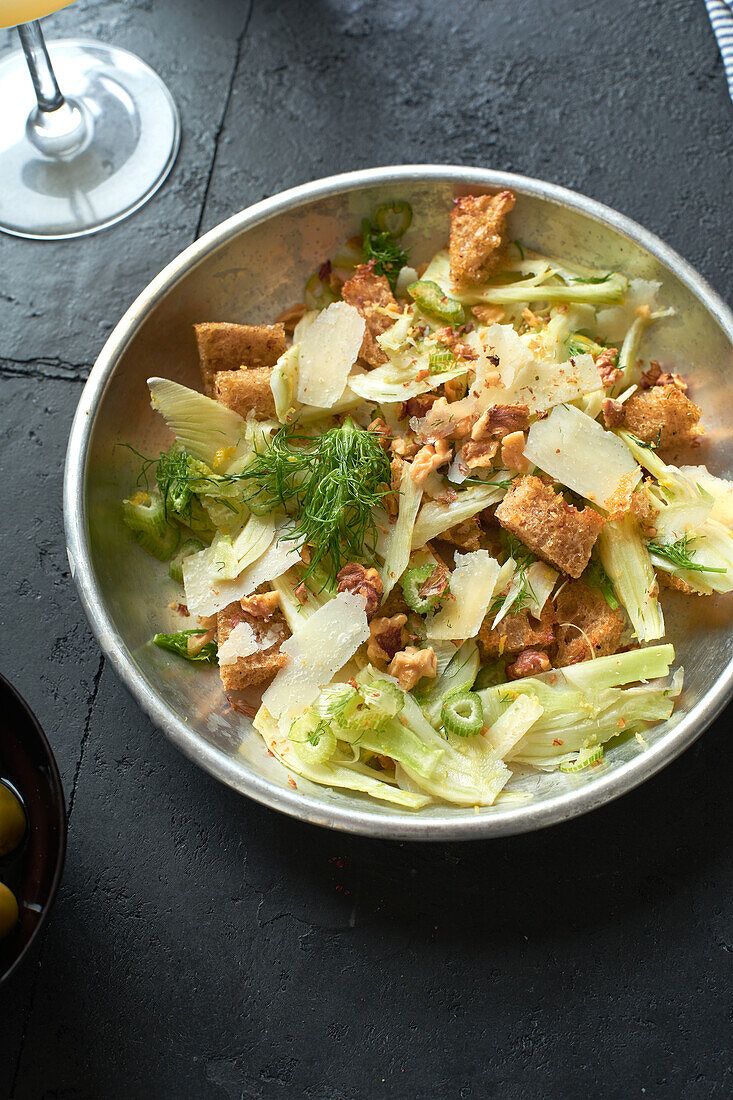 From above fennel salad with parmesan cheese, walnuts and croutons on grey background