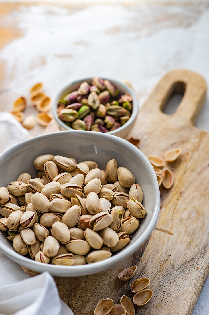 Ceramic bowl with organic pistaschio nuts on white wooden table background