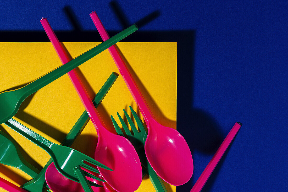 Overhead view of bright colorful eco friendly cutlery near yellow carton sheet