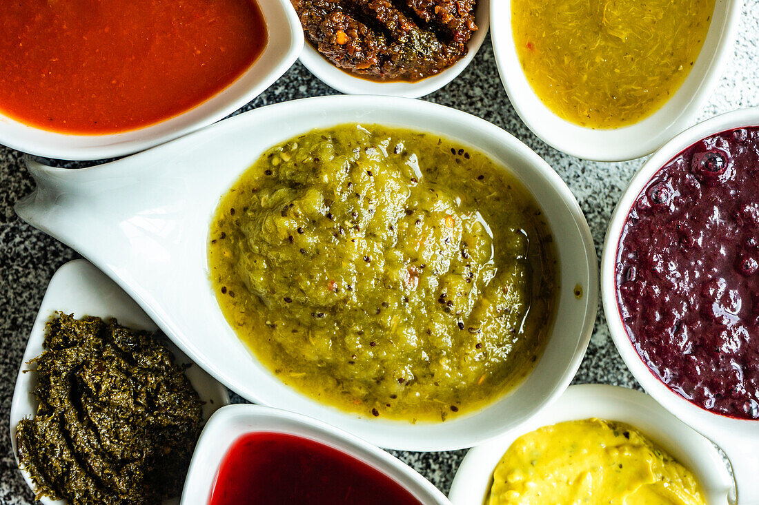 Traditional georgian cooking concept with variety of spices, sauces and herbs in ceramic bowls on grey concrete background