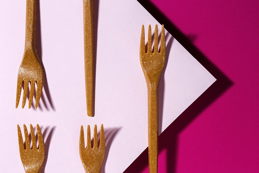 From above view of brown eco friendly fork on pink carton background