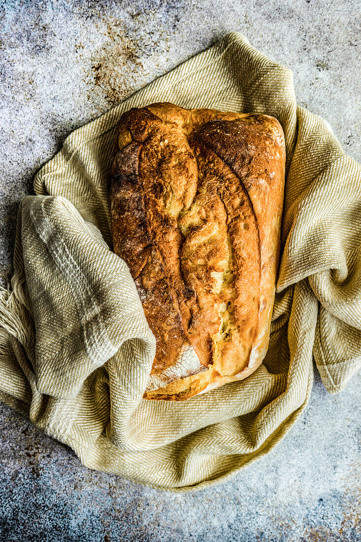 Draufsicht auf einen frisch gebackenen Laib Brot, der auf einer Serviette in der Küche liegt