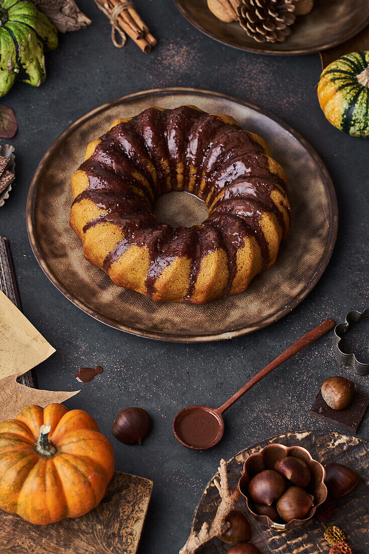 Von oben leckerer Kürbiskuchen mit Schokoladencreme auf einem mit Herbstgemüse dekorierten Tisch