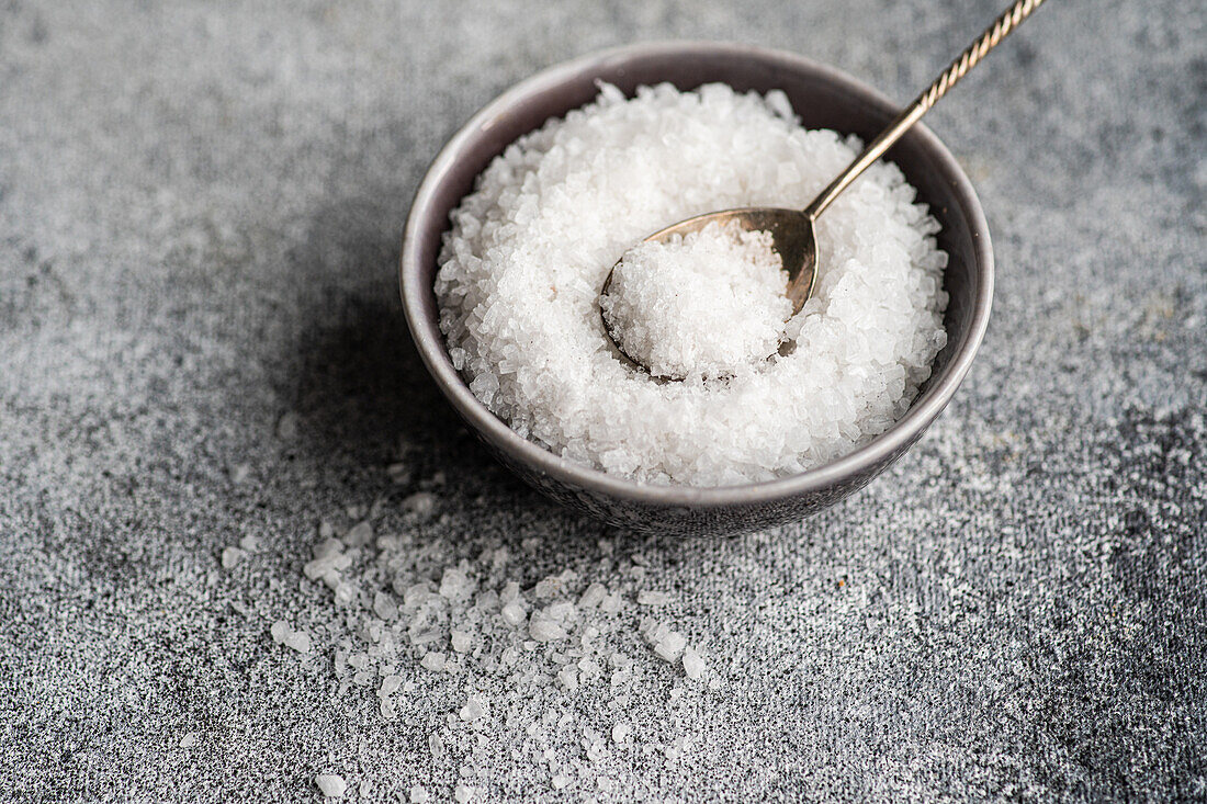 From above cooking concept with sea salt in ceramic bowl on concrete table