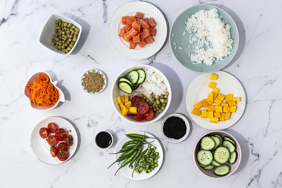 Top view of assorted fresh ingredients for traditional oriental poke preparation placed on marble tabletop