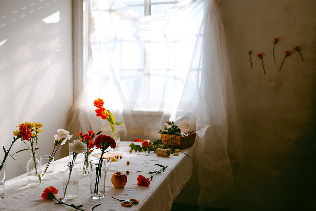 Gläser mit frischen Tulpen und Nelken in Wasser auf dem Tisch für Blumensträuße