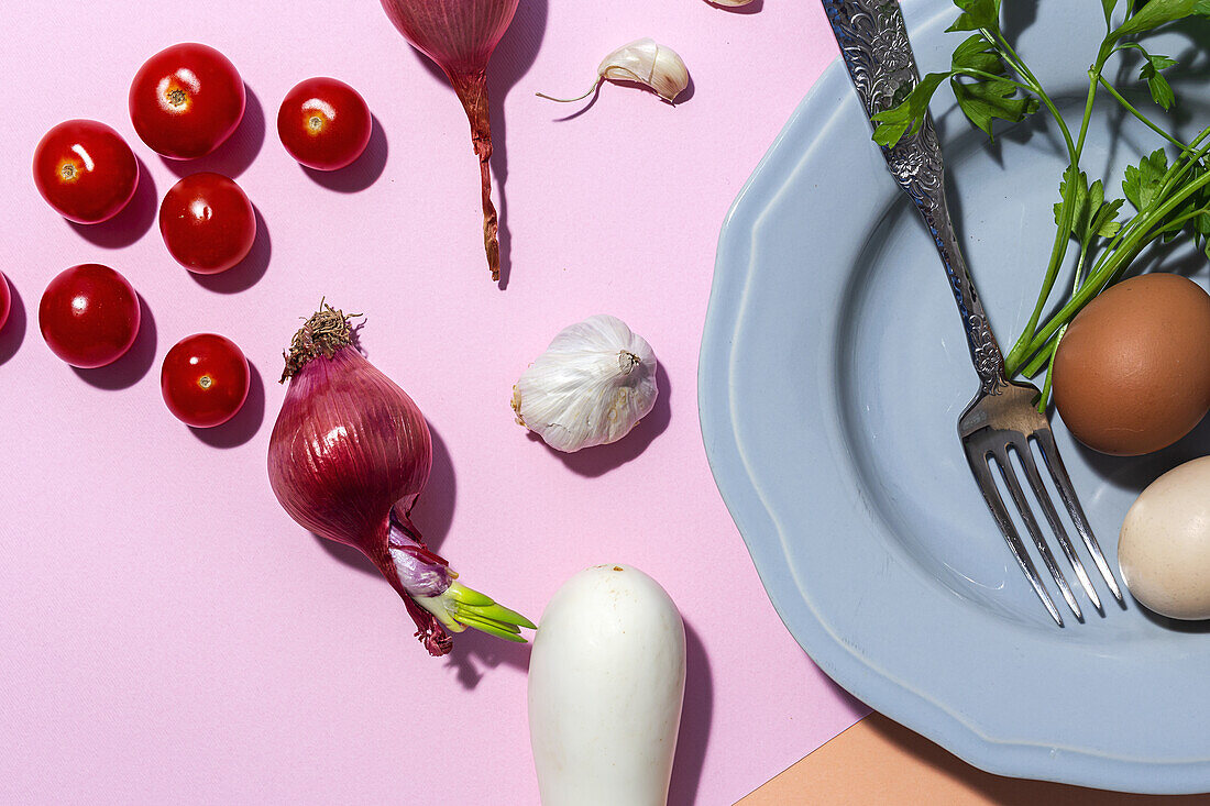 Top view of chicken eggs on plate with fork against fresh parsley sprigs and cherry tomatoes on two color background